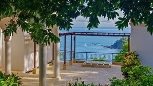 A covered outdoor area with a view of the sea, featuring a pergola structure and stone flooring. -  Panoramic Ocean views Waterfront Luxury Home  (Jaco)