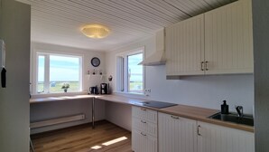 Een keuken met witte kastjes, een houten aanrecht, een spoelbak en een raam met uitzicht op de omgeving.