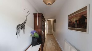 A hallway with a giraffe wall decal, a staircase, and a framed painting.