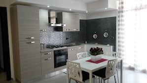 Una cocina moderna con una isla central, electrodomésticos de acero inoxidable y un salpicadero oscuro.