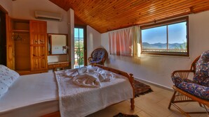 Ein Schlafzimmer mit Holzboden, einem Bett mit weißer Bettdecke, einem Schrank aus Holz, einem Stuhl und einem Fenster mit Bergblick.