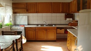 Une cuisine avec des meubles de rangement en bois, une cuisinière, un évier et un réfrigérateur.