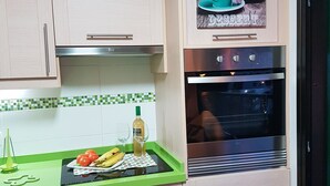 A kitchen with light-colored cabinets, a green countertop, a built-in oven, and a wall-mounted sign above the oven. - Playa Chica Apartment (SANTA CRUZ DE TENERIFE)