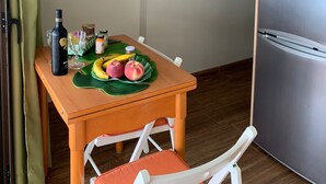 A dining area with a wooden table, chairs, a clock on the wall, and a refrigerator. - Playa Chica Apartment (SANTA CRUZ DE TENERIFE)