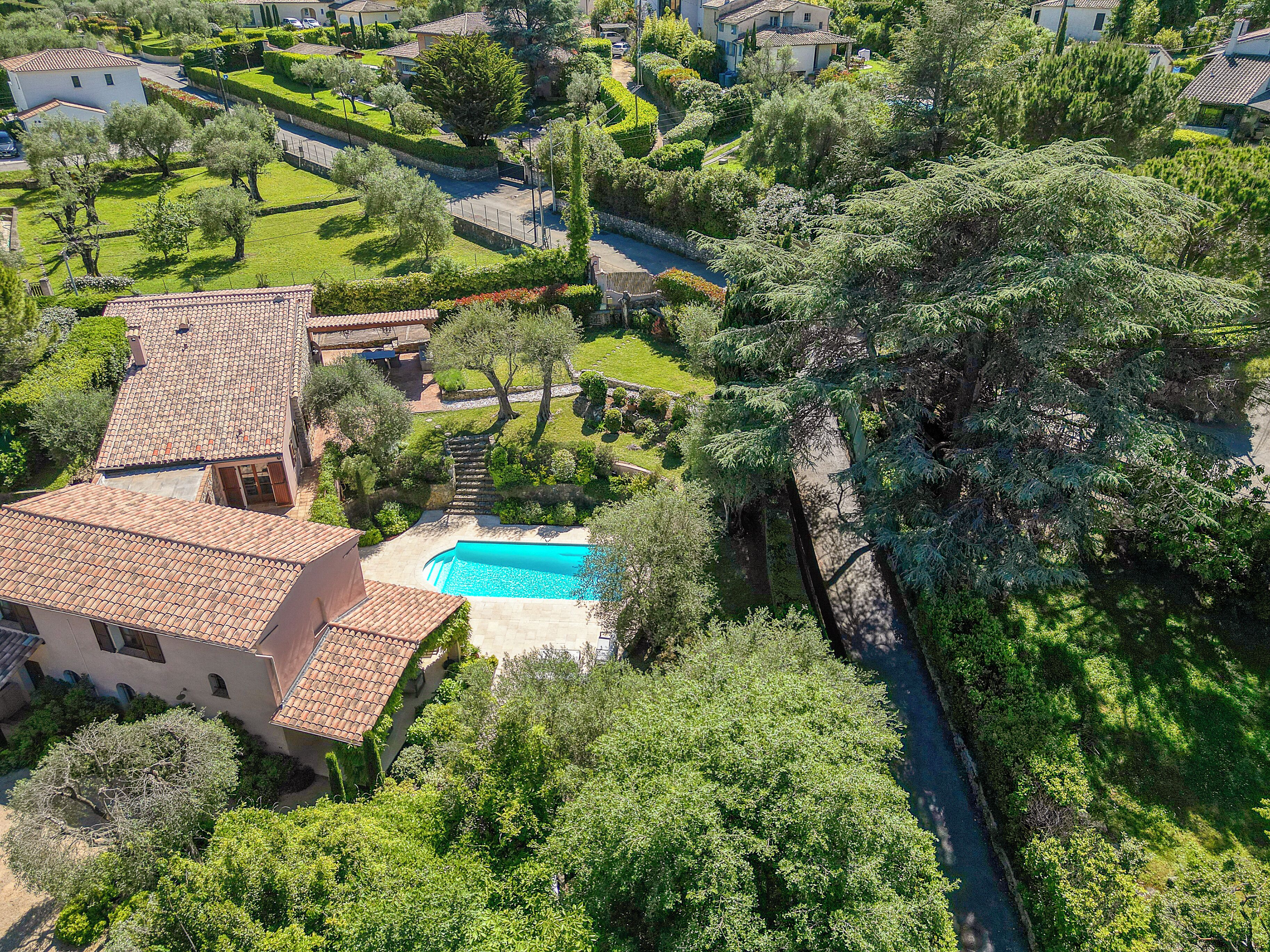 A residential property with a swimming pool, terraced garden, and a stone pathway.