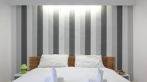 Ein Hotelzimmer mit einem großen Bett, einem gestreiften Kopfteil und ordentlich gefalteten Handtüchern.
