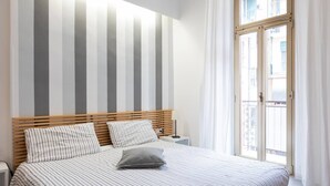 Ein Schlafzimmer mit gestreifter Bettdecke, einem hölzernen Kopfteil und einem Nachttisch mit Lampe.