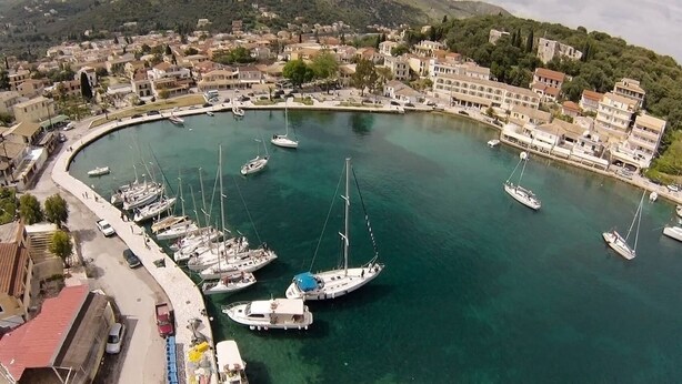 Un port de plaisance où sont amarrés de nombreux bateaux, entouré de bâtiments et d’un paysage vallonné.