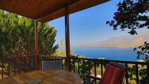A wooden deck with a table and chairs, overlooking a body of water and mountains. - Kas Holiday Rental with Stunning Sea View and Swimming Pool ( 6 people ) (Turquoise Coast East)