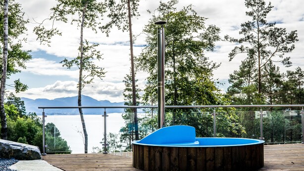 A wooden deck with a hot tub, overlooking a lake with mountains in the background. - New, large family friendly cottage, with great views, in rural surroundings (Fusa)