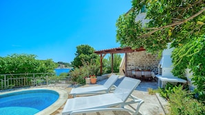 A pool area with lounge chairs, a pergola, and a stone wall. - Traditional Villa Bonaca in Sumartin with private pool, Brač Island, near sea (Sumartin)