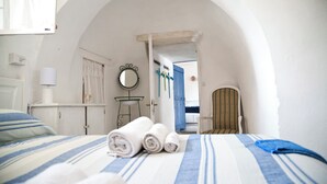 A hotel room with a bed, a chair, a mirror, and a door leading to another room. - Authentic Trullo with swimming pool in Itria Valley Apulia (Martina Franca)