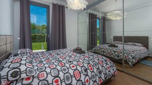 A bedroom with a large bed, a mirror, and a view of the outdoors. - Villa Lagoderan Rovinj (Rovinj)