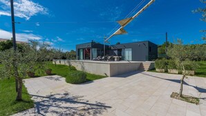 A modern house with a patio, outdoor seating, and a large umbrella. - Villa Lagoderan Rovinj (Rovinj)