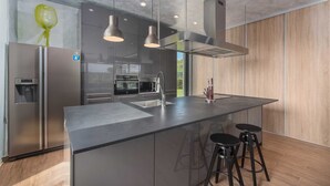 A modern kitchen with a central island, stainless steel appliances, and bar stools. - Villa Lagoderan Rovinj (Rovinj)