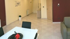 A hotel room with a dining area, a hallway, and a door leading to another room.