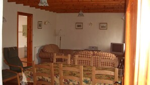 Una habitación acogedora con techo de madera, una cama con ropa de cama de cuadros, un televisor y una silla.