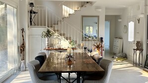 A spacious dining area with a large wooden table, modern chairs, and a view of the kitchen and living space.