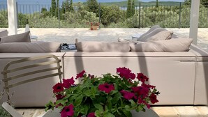 A covered outdoor seating area with a view of mountains and a lake.
