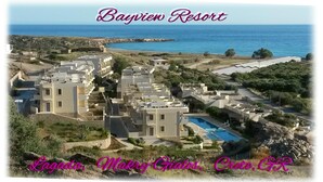 A resort with multiple buildings, a swimming pool, and a view of the sea.
