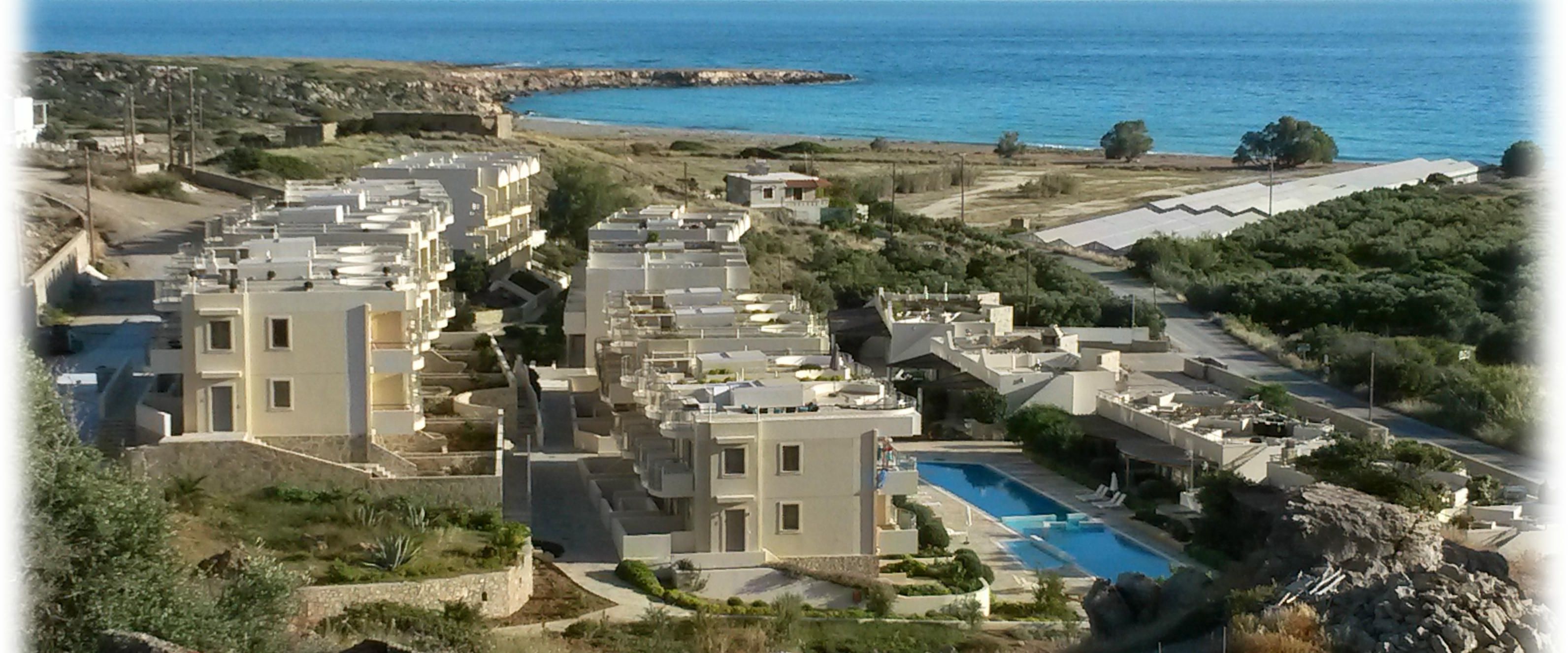 Un resort con varias construcciones, una piscina y vistas al mar.
