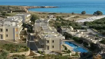Un resort con varias construcciones, una piscina y vistas al mar.