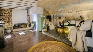Un intérieur rustique avec des murs en pierre, une cheminée, un canapé vert et un fauteuil jaune.