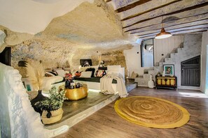 Un intérieur rustique avec des murs en pierre apparentes, un plancher en bois, un canapé, une table basse et un escalier.