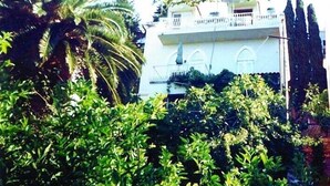 Un edificio de varios pisos con balcones, rodeado de abundante vegetación.