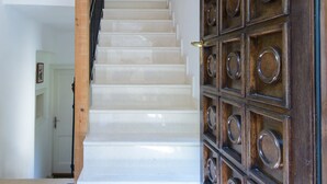 Una escalera con barandilla de madera que lleva a una puerta con paneles circulares.