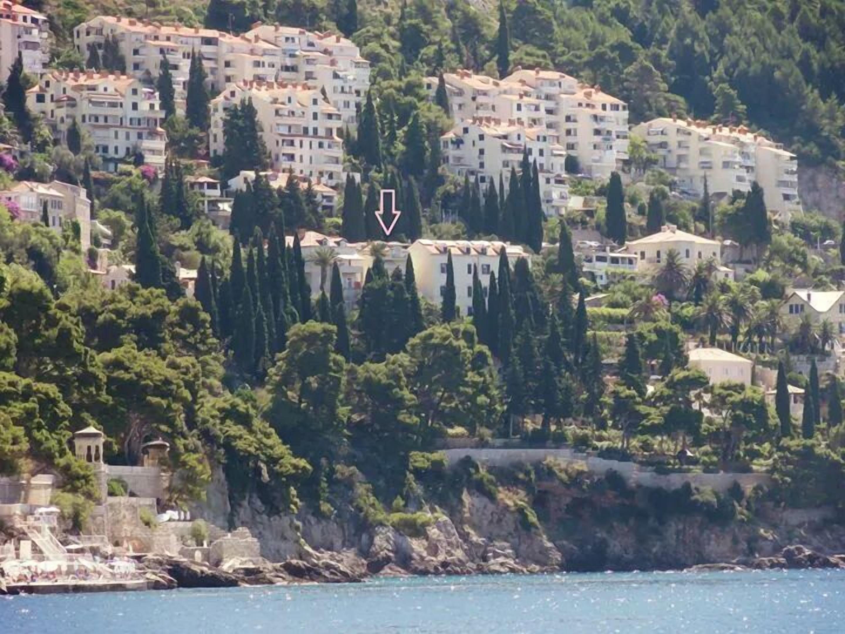 Un quartier résidentiel situé sur la côte, caractérisé par des immeubles à plusieurs étages, une végétation luxuriante et une côte rocheuse.