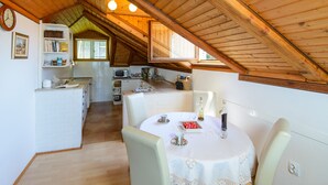 Una cocina acogedora con vigas de madera, un comedor con una mesa lista para dos personas y una pared de ladrillo blanco.