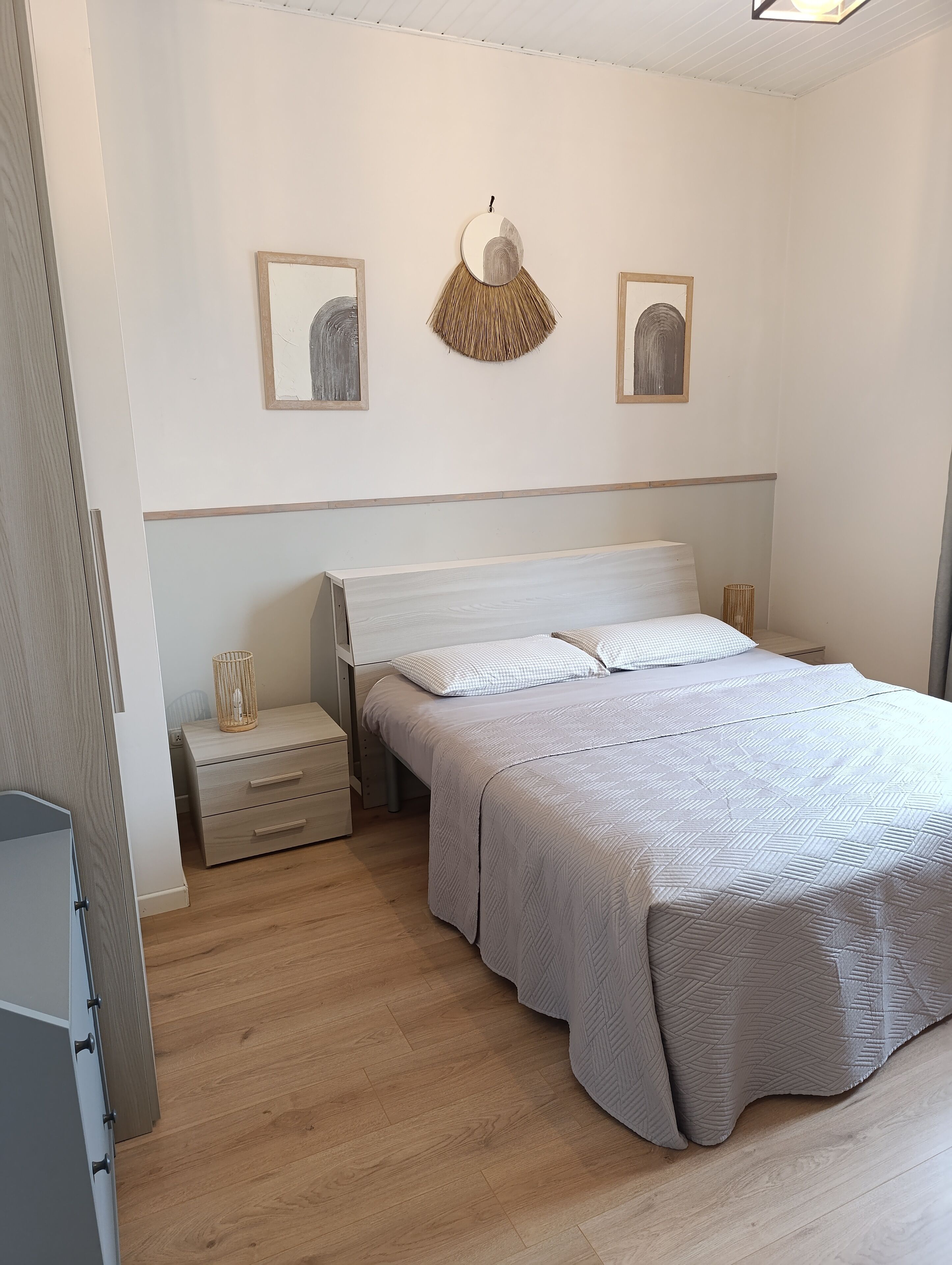 Un dormitorio con cama, mesitas de noche y decoración en la pared.