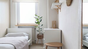 Un dormitorio moderno con cama, mesita de noche y una planta en maceta.