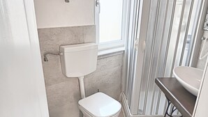 Un baño pequeño con inodoro, lavamanos y zona de ducha.