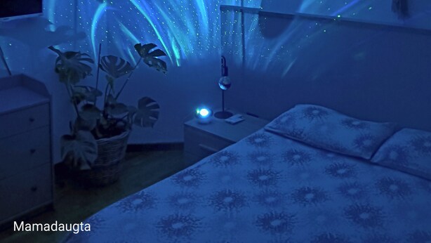 Una habitación con una cama, una mesita de noche, una lámpara y un televisor instalado en la pared.
