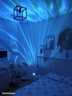 Une chambre avec un lit, une table de chevet, une lampe et un téléviseur fixé au mur.