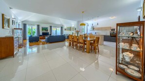 A spacious living area with a dining table, sofas, and a kitchen in the background.