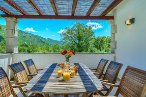 A round wooden table with six chairs, a vase with red flowers, and a glass of orange juice. - Villa Župa in Dalmatian Hinterland with private pool near Biokovo (Župa)