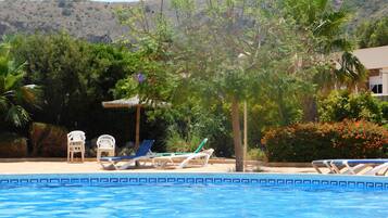Relax by the serene pool surrounded by lush greenery and palm trees.