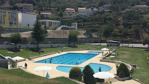 A swimming pool with multiple lanes, surrounded by a grassy area with umbrellas and seating.