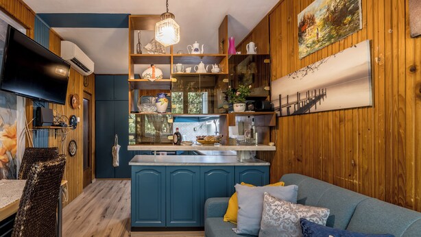 A cozy kitchen with blue cabinets, a wooden dining area, and a blue sofa with patterned cushions. - BUDGET Split City Apartment with 3 Bedrooms, A/C and WI-FI Internet (Split)