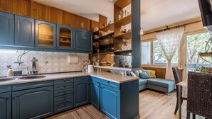 A modern kitchen with blue cabinets, a wooden island, and a dining area with a blue sofa and wicker chairs. - BUDGET Split City Apartment with 3 Bedrooms, A/C and WI-FI Internet (Split)