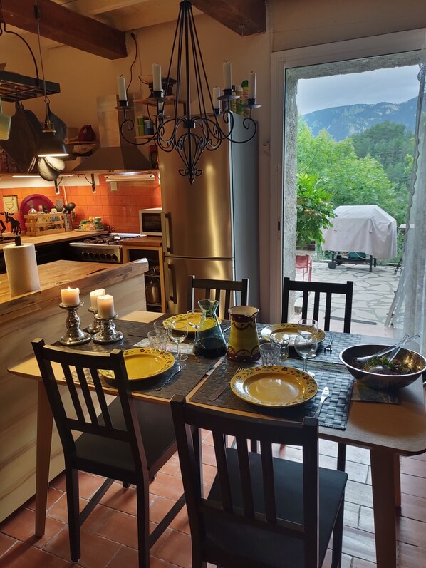 A dining area with a table set for six, a chandelier, and a view of the outdoors.