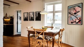 Un comedor con muebles de madera, un ventanal grande y obras de arte en las paredes.