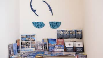 Una exhibición de folletos y libros de viajes sobre una mesa, con una obra de arte en la pared superior.