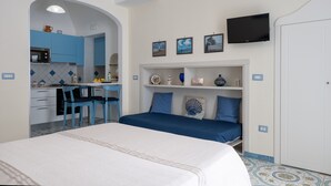A bedroom with a bed, a TV, and a kitchenette. - Libeccio - flat with terrace & sea view, perfect for up to 3 guests (Maiori)