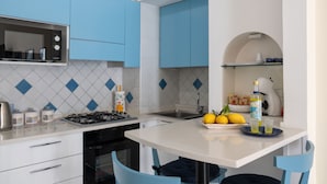 A modern kitchen with blue cabinets, a white countertop, a gas stove, and a sink. - Libeccio - flat with terrace & sea view, perfect for up to 3 guests (Maiori)