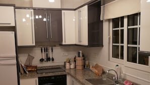 Una cucina moderna con mobili bianchi, un lavello in acciaio inossidabile e un forno integrato.