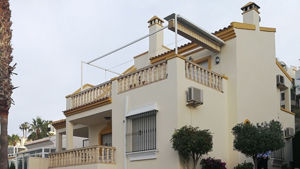 Edificio residenziale con piscina, area relax esterna e parete in pietra.